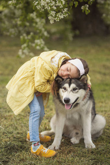 Girl embracing dog while standing at park