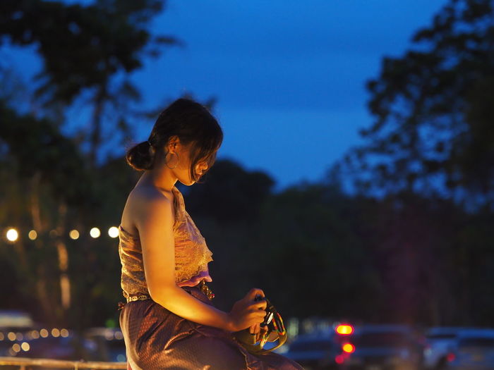 Side view of woman against sky at night