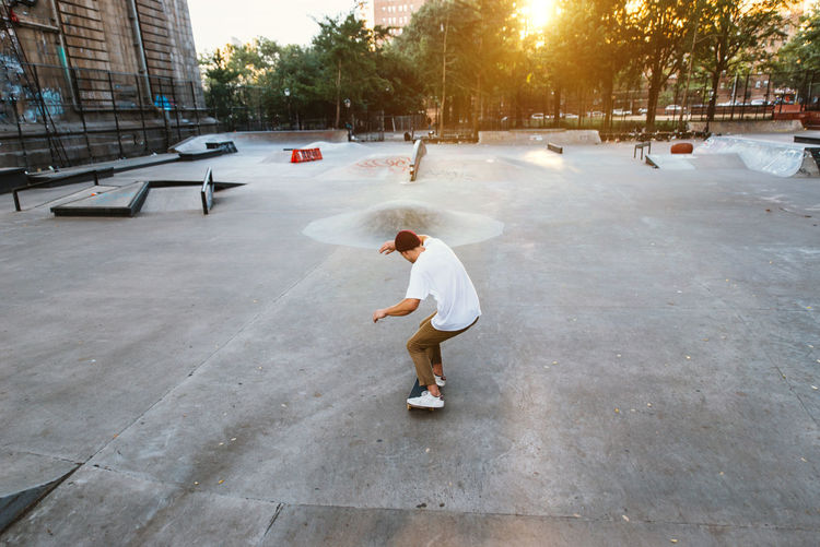 Full length of man skateboarding at skating park against building