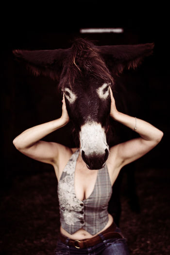 Woman hiding face behind donkey head