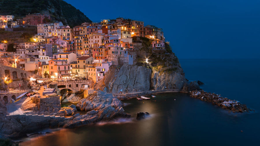 Aerial view of illuminated buildings by sea
