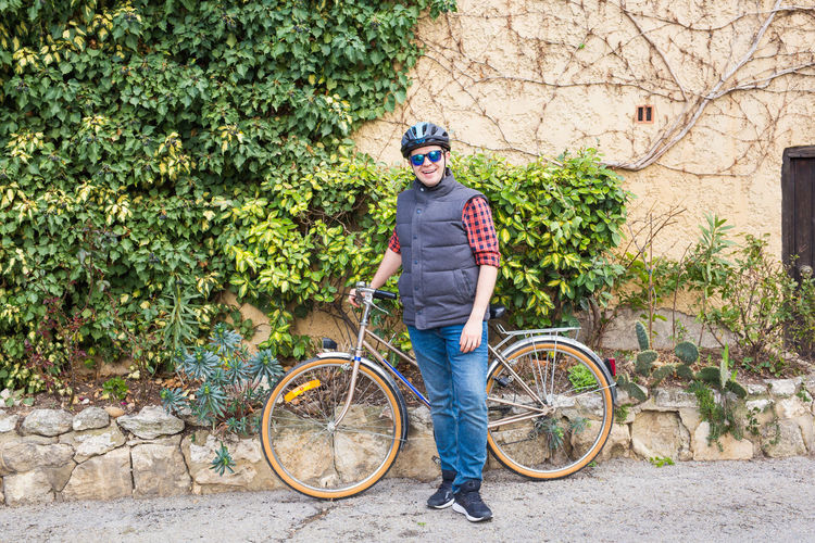 Portrait of smiling boy with bicycle standing against plants