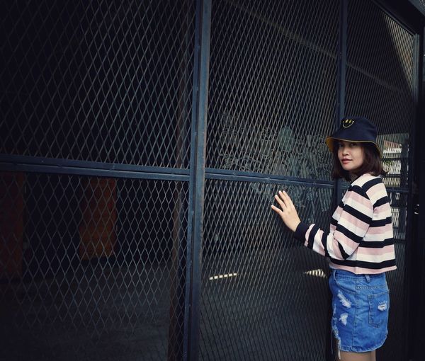 Portrait of girl standing against fence