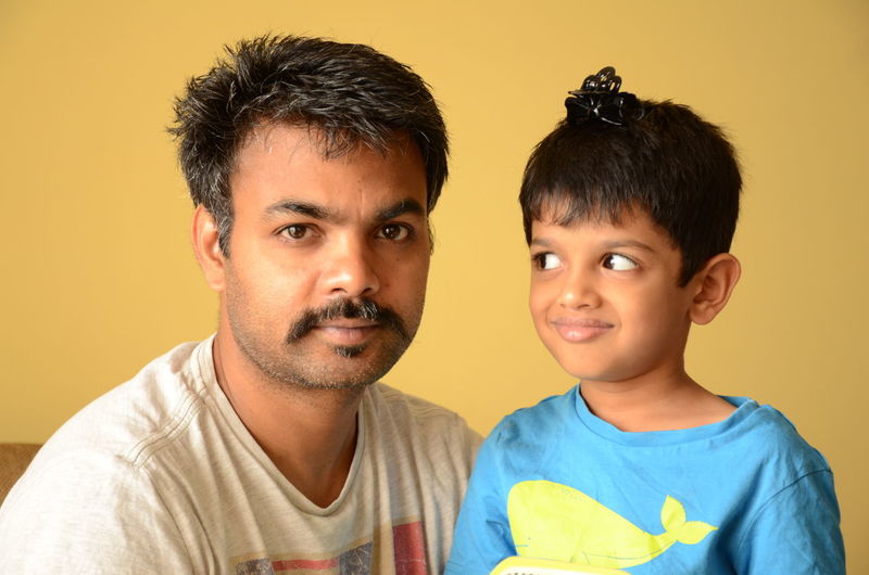 Portrait of father and son against wall at home
