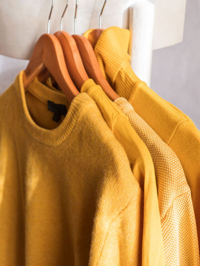 Yellow illuminated color winter sweaters on wooden hangers. trendy fashion autumn warm  clothes.