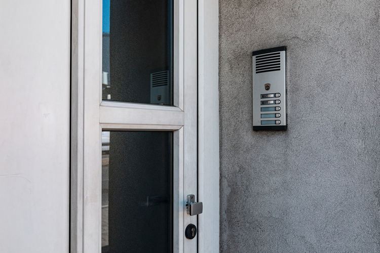Intercom on gray wall next to the front door on street