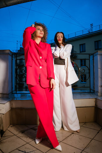 Two beautiful fashionable women posing in the evening on the city street