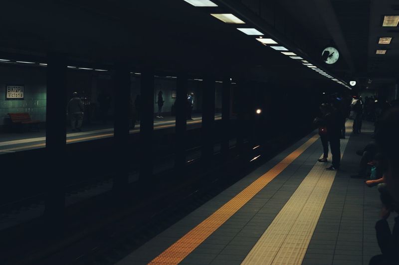 People waiting at railroad station platform at night
