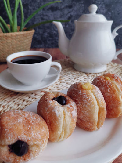 Close-up of cup of coffee and doughnuts on table
