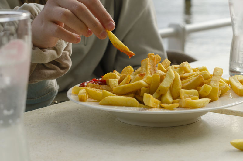 Kid eating french fries with tomato sauce