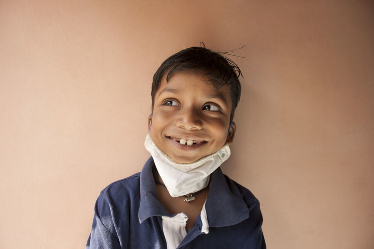 Close-up of smiling boy wearing mask against wall