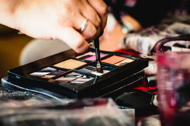 Cropped hand of woman using eyeshadow at home
