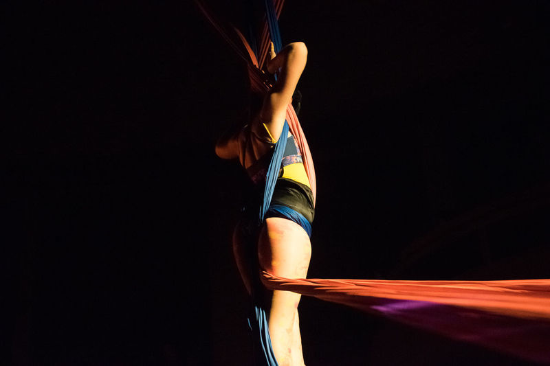 Side view of woman practicing acrobatics against black background