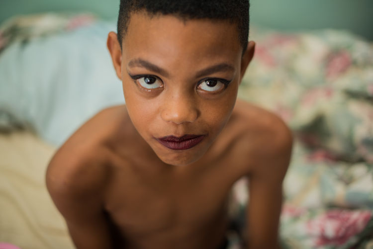 High angle portrait of shirtless boy wearing make-up at home