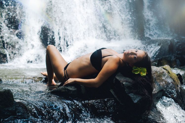 Woman lying in front of waterfall
