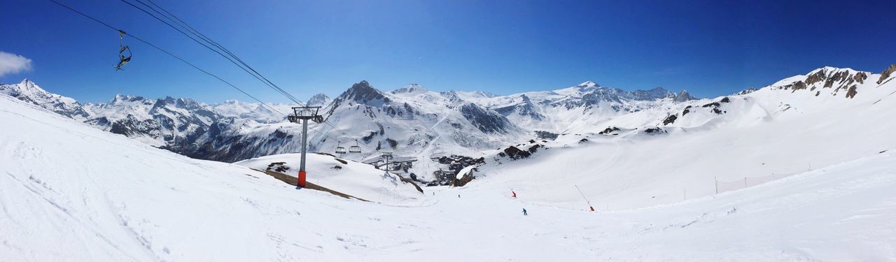 Panoramic view of snow covered mountain against blue sky