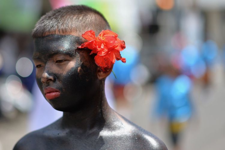 Close-up of boy with painted body wearing red flower