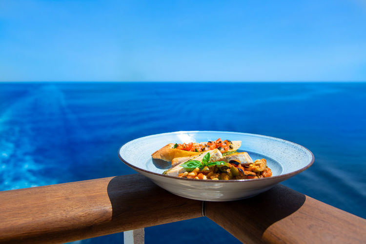 Food on table by sea against blue sky