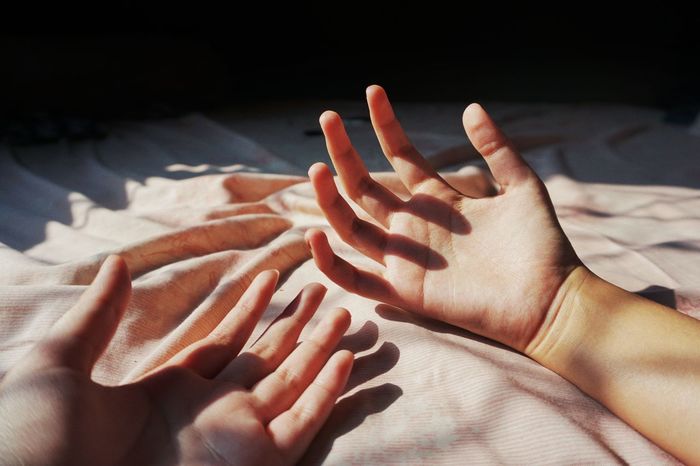 Cropped hands of people on bed at home