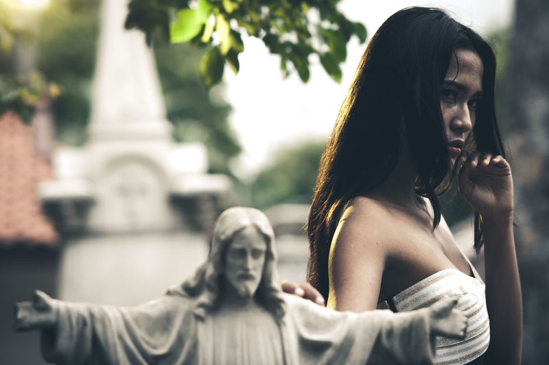 Woman standing statue against trees