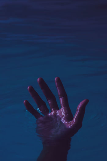 Cropped hand drowning in lake at night