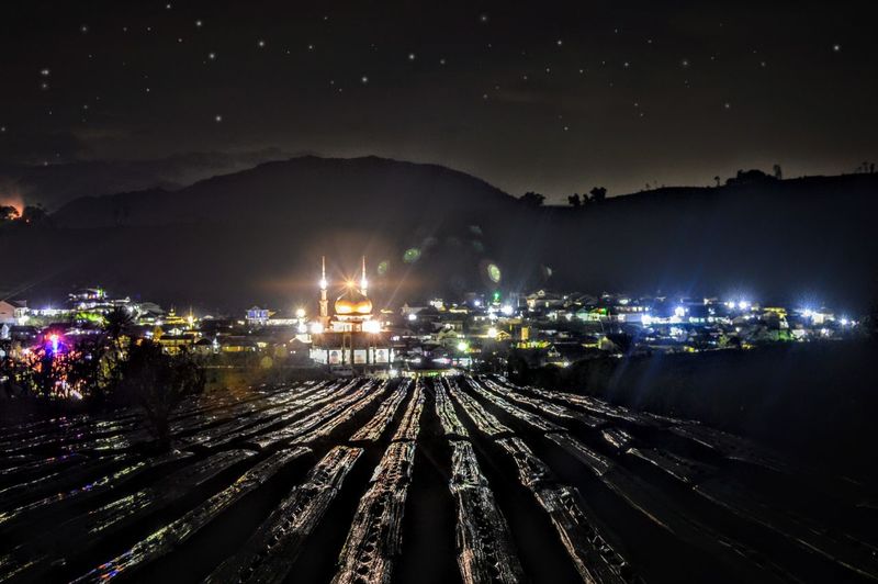 High angle view of illuminated railroad tracks against sky at night