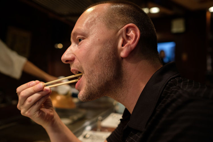 Close-up of man eating with chopsticks