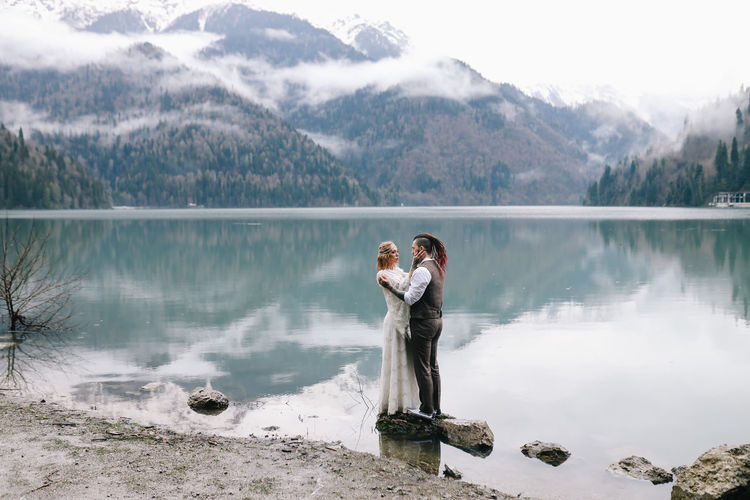 A happy couple in love and married embrace in nature by the lake and the misty mountains