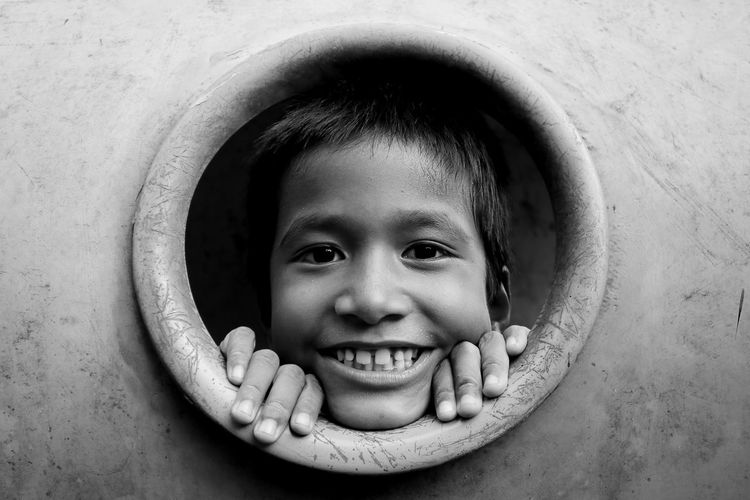 Portrait of smiling boy peeking through hole