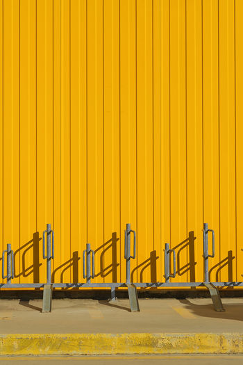 Vertical shot of bike parking near a bright yellow profiled metal wall, fence or warehouse idea, 