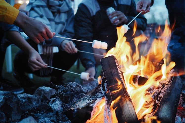 Low section of people having marshmallows on barbecue