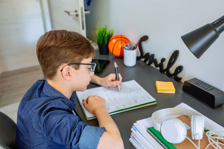 Boy writing in book on table