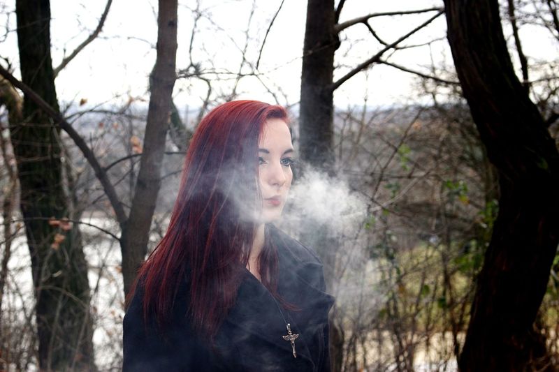 Woman exhaling smoke in forest