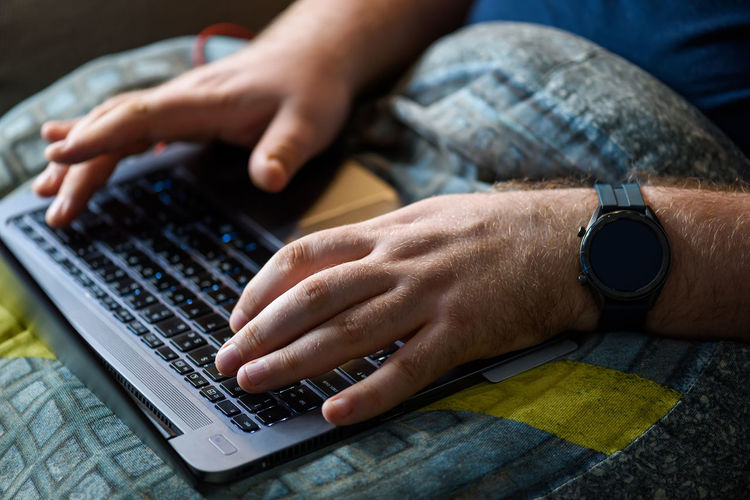Cropped hands of man using laptop at home