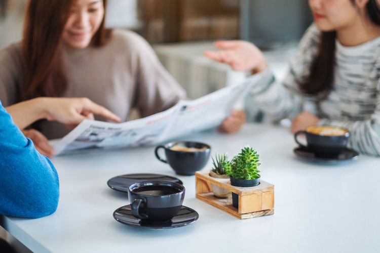 Male and female friends sitting by table for coffee at cafe