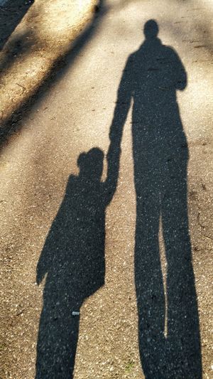 Shadow of man and woman standing on road