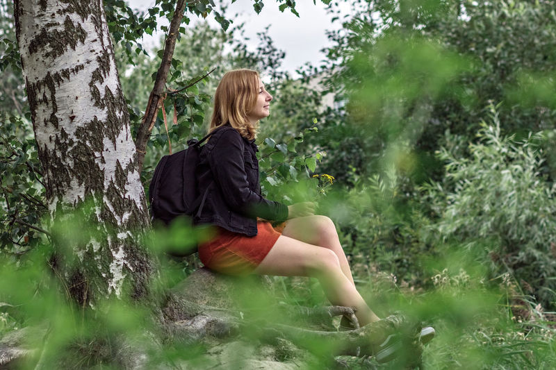 Rear view of woman sitting in forest