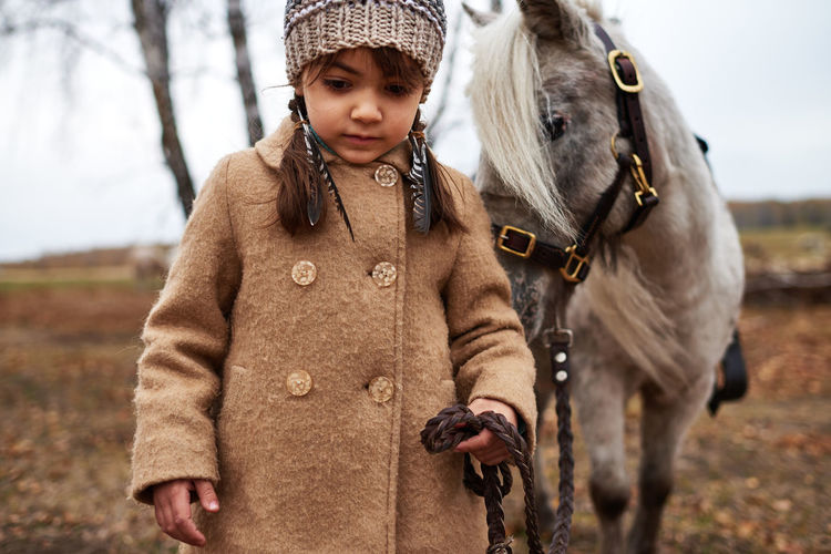 Beautiful girl leading her pony by bridle