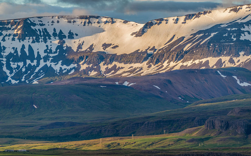 Rugged mountain range dominates the dramatic scenery during a brief icelandic summer near sunset