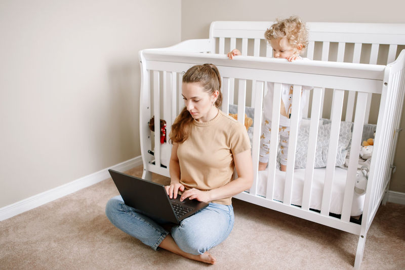Caucasian mother with baby working on laptop from home. workplace of freelancer 