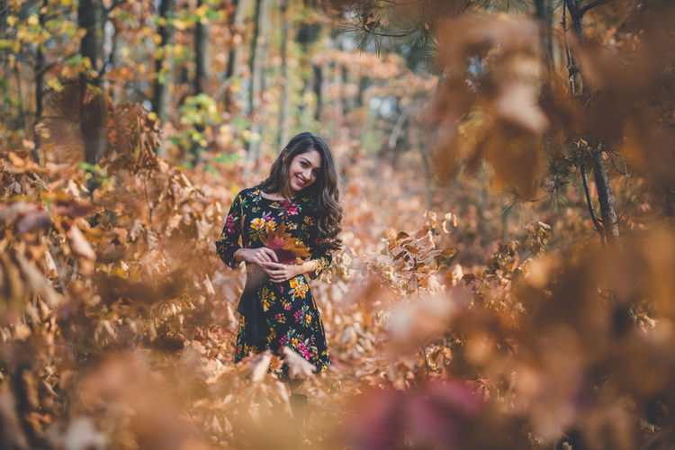 Full length of woman standing amidst trees during autumn