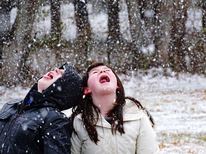 Girl with boy wearing warm clothing during snowfall