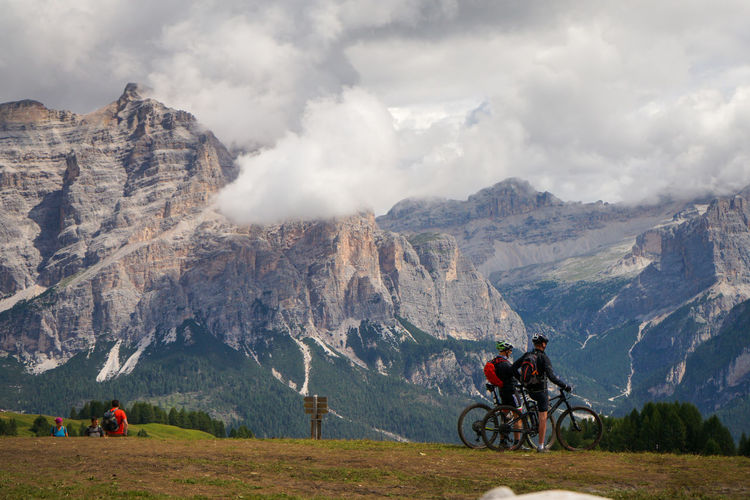 People riding bicycle on mountain against sky