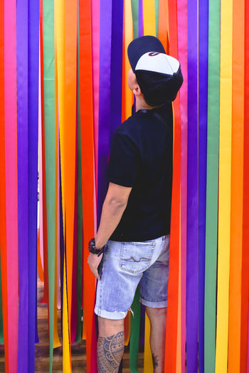 Rear view of man standing against multi colored curtain