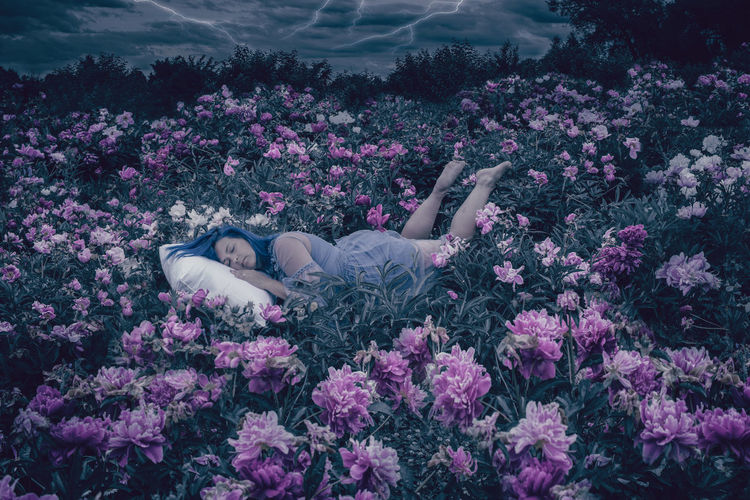 Low section of person relaxing on purple flowering plants