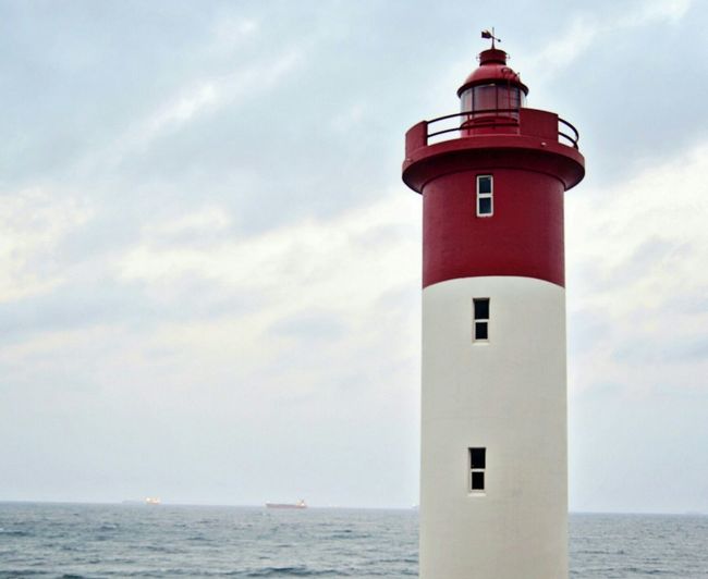 Lighthouse by sea against sky