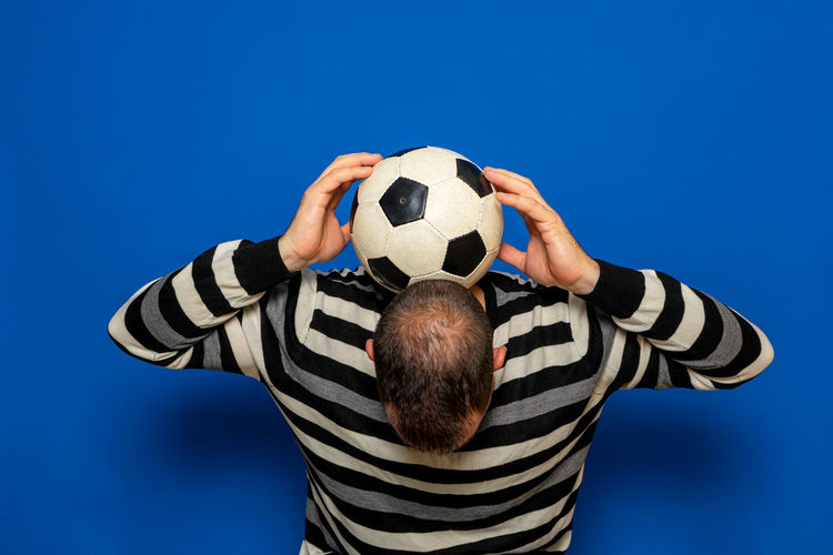 Midsection of man with soccer ball against blue sky