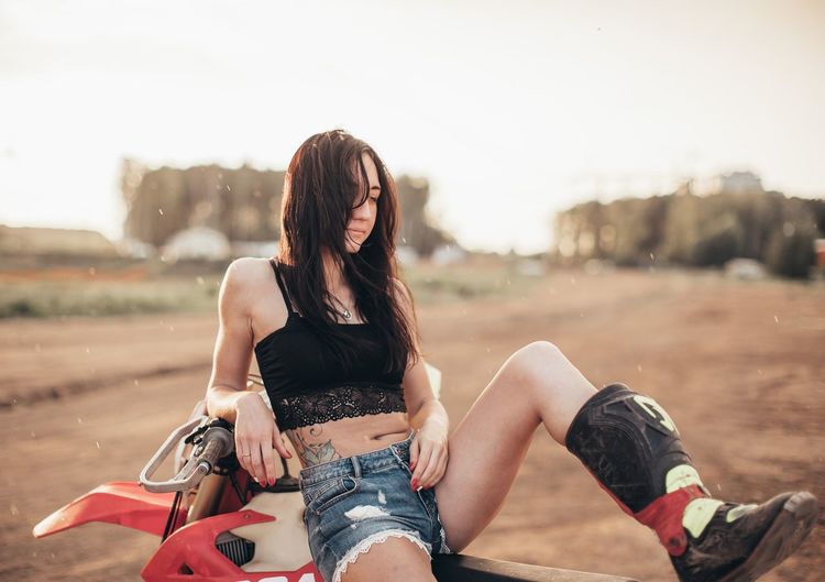 Young woman sitting on motorcycle outdoors