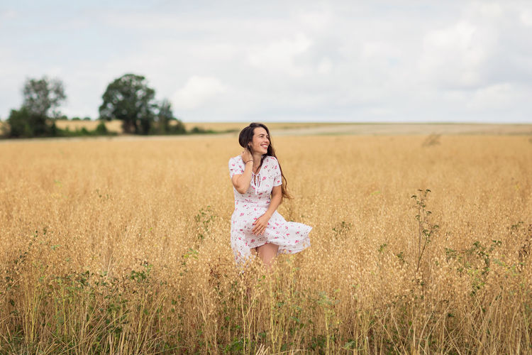 Young woman in white midi dress walking across the field
