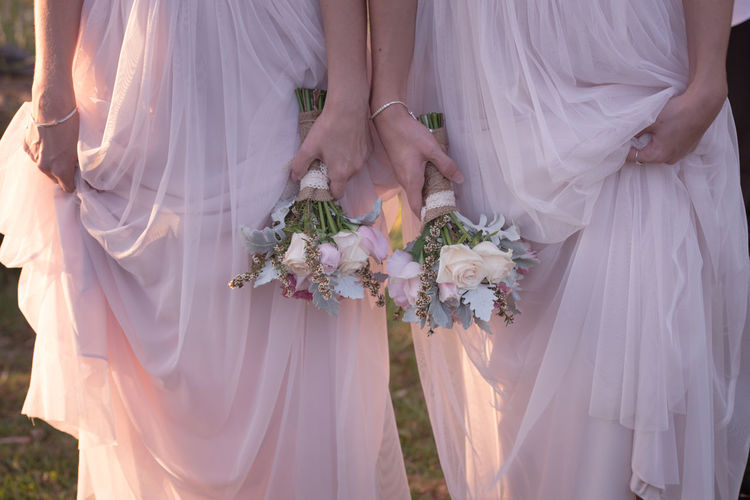 Midsection of bridesmaids holding bouquets